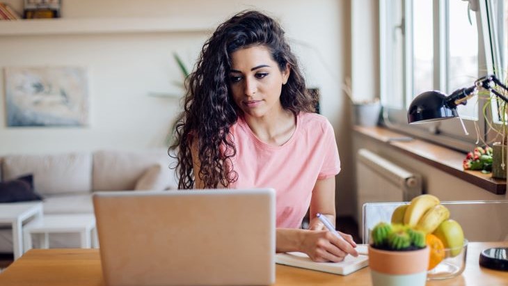 Alt - Woman working or applying on laptop and taking notes 