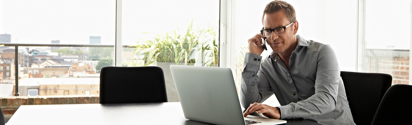 Man on phone and working on a laptop