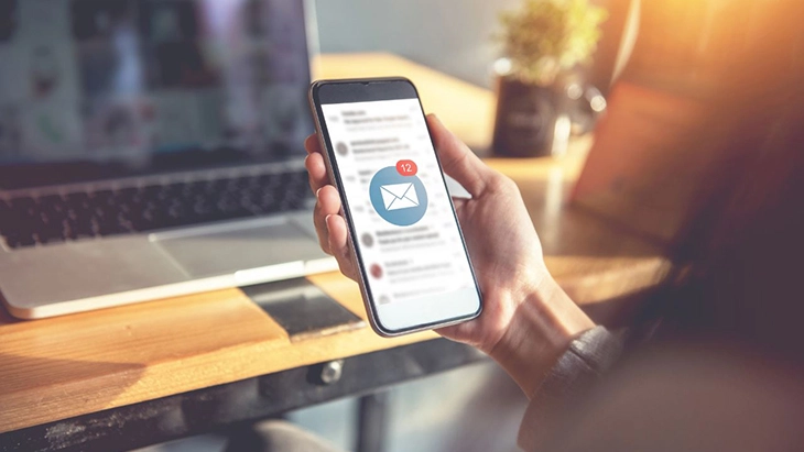 Hand holding smartphone in workspace