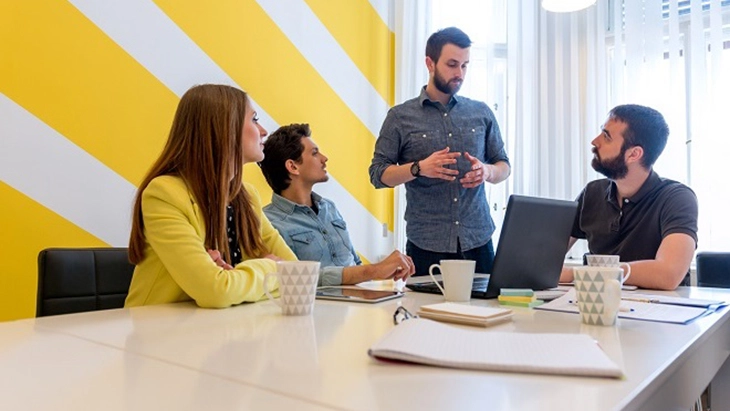 Three men and a woman in discussion around a conference table