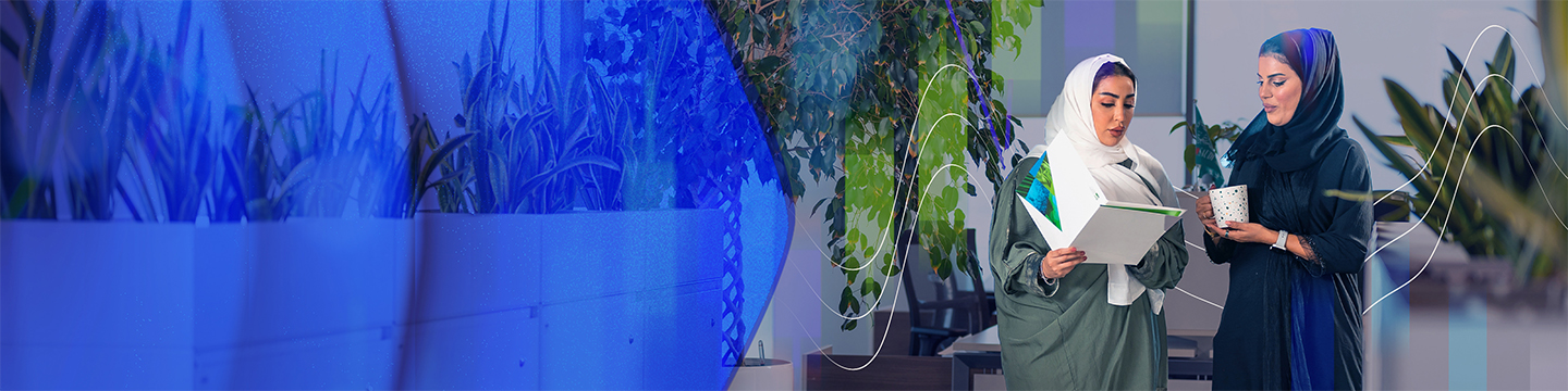 Two individuals standing in an office setting, one holding an open folder and the other holding a coffee mug, with green plants and abstract wave graphics in the background