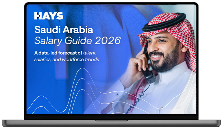 Laptop screen displaying the Hays Belgium Salary Guide 2026 cover, featuring text on a blue background with a person in business attire in the foreground and others in the background.